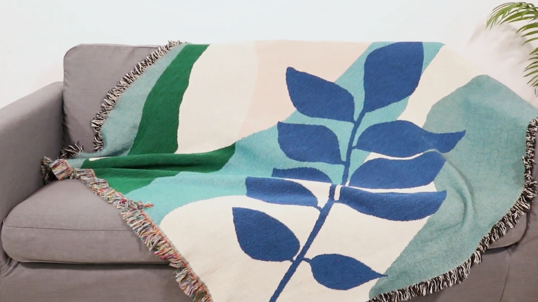 Tapestry blanket with blue leaf design on a sofa