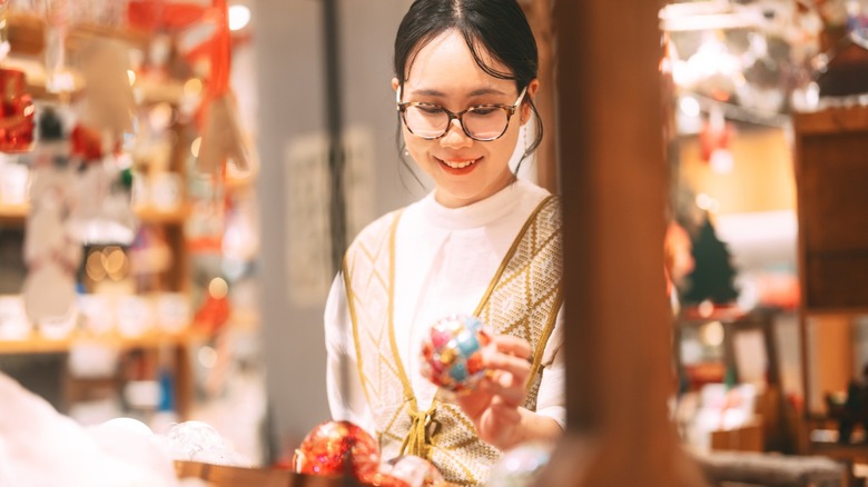 A shopper holding a colorful Christmas ornament in a store
