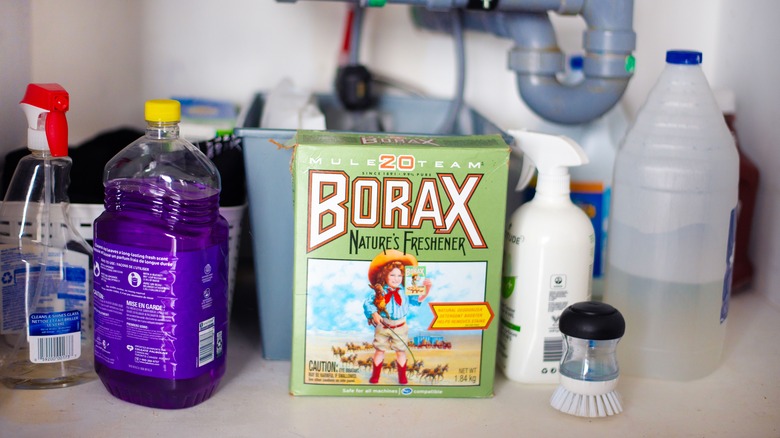 A green box of borax with other cleaning supplies.