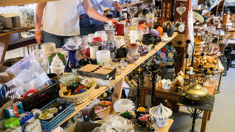 People shop at a thrift or secondhand store with a variety of items on a table