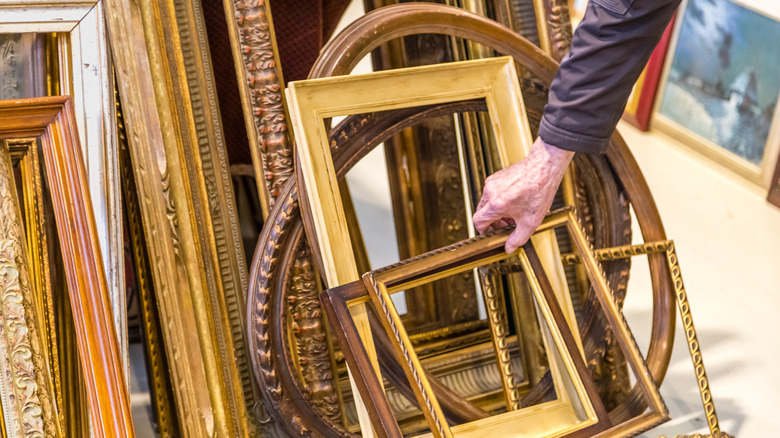 Man reaching for a vintage picture frame at a thrift store