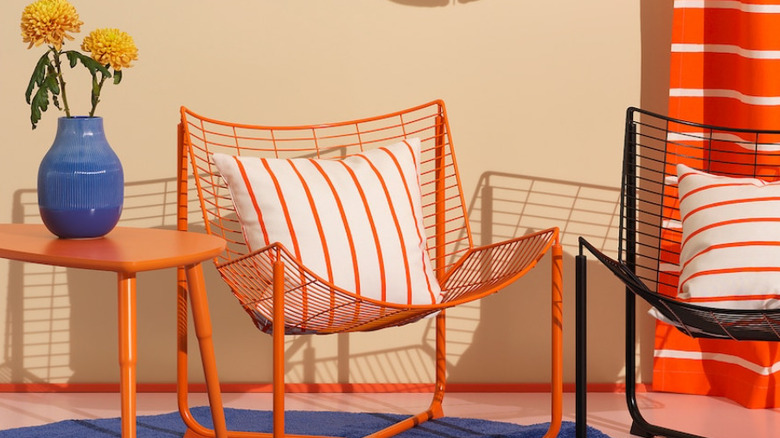 An orange wire IKEA accent chair with a white striped pillow