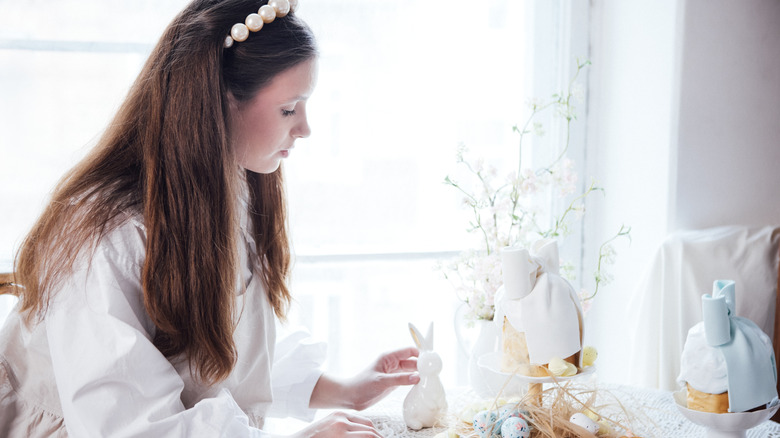 A woman decorates with vintage pastel Easter decor