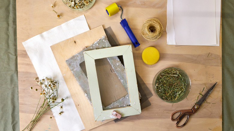 Paper, wood, and picture frame art supplies on a wooden craft desk.
