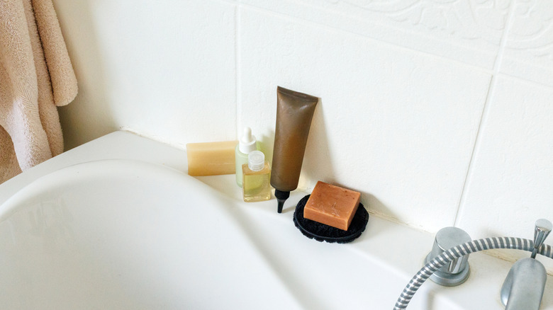 A bathtub ledge with toiletry products.