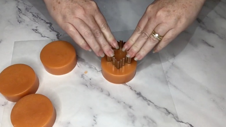 Person using aluminum cookie cutters to cut shapes for DIY soap.