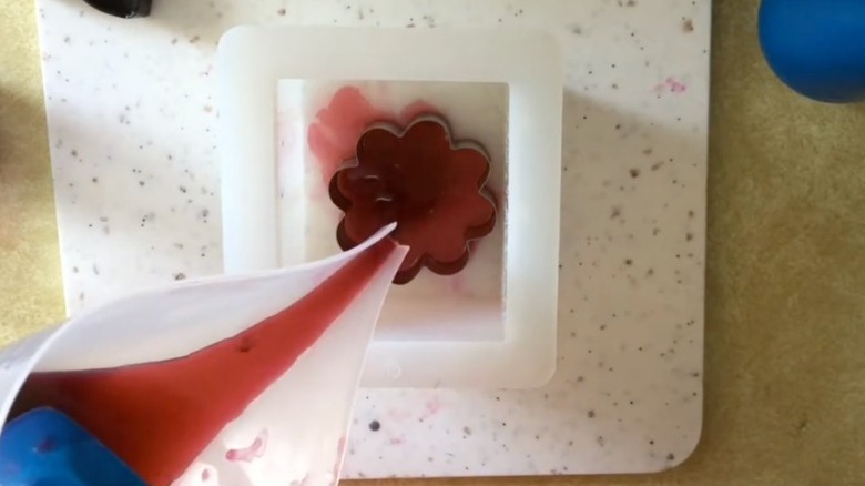 DIYer pours melted melt and pour soap into a vintage cookie cutter to DIY soap at home.