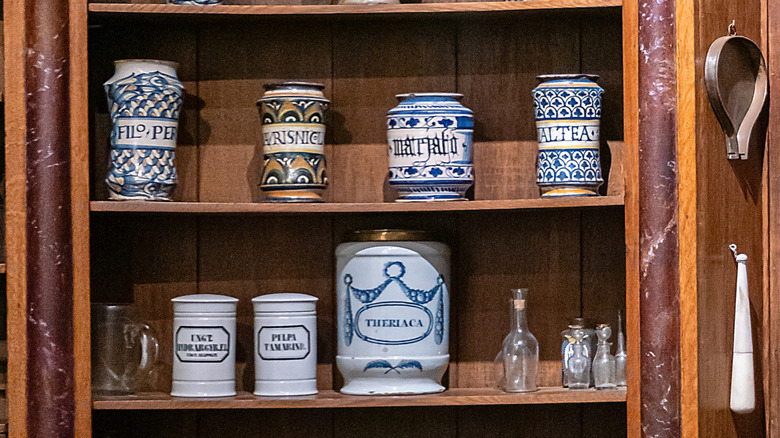 White apothecary jars with blue and brown accents on wooden shelves
