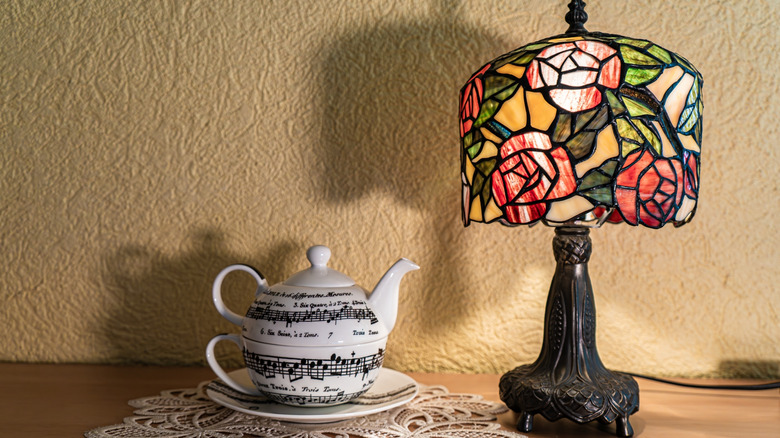 Tiffany lamp with roses styled on chic vintage table with teapot