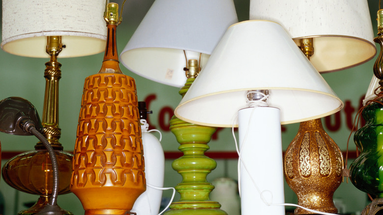 row of colorful vintage lamps on a thrift store shelf