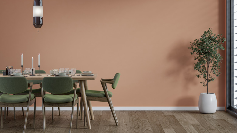 Dining room with peach walls, light wood dining table, and green upholstered chairs