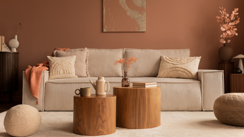 Living room with warm, rose walls paired with wood furniture, cream couch, and boucle pillows and accents