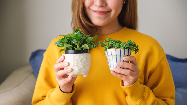 A woman holding two small potted plants while smiling