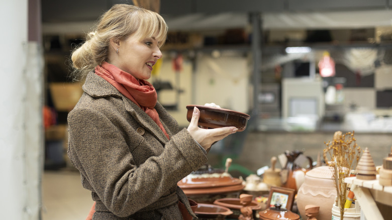 A woman looking at ceramics and kitchen items at a flea market