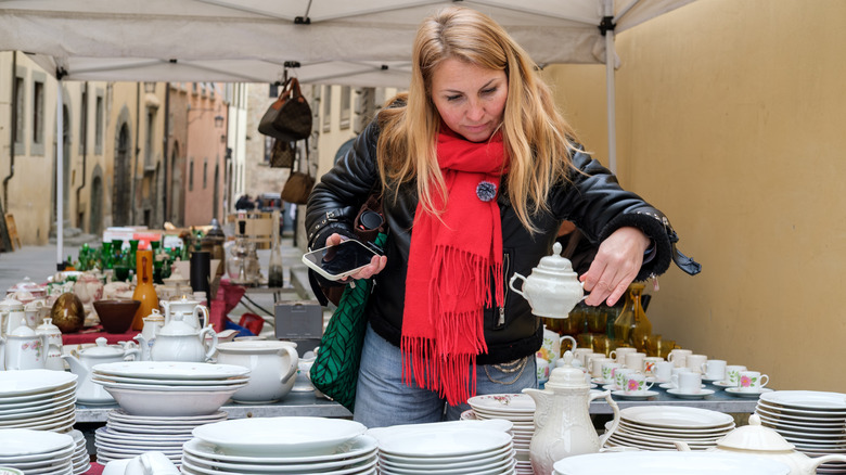 A woman looking through vintage ceramic dishware