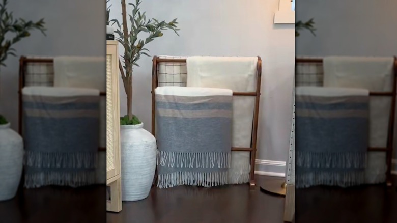 Vintage wooden quilt rack being used to organize throw blankets in a living room.
