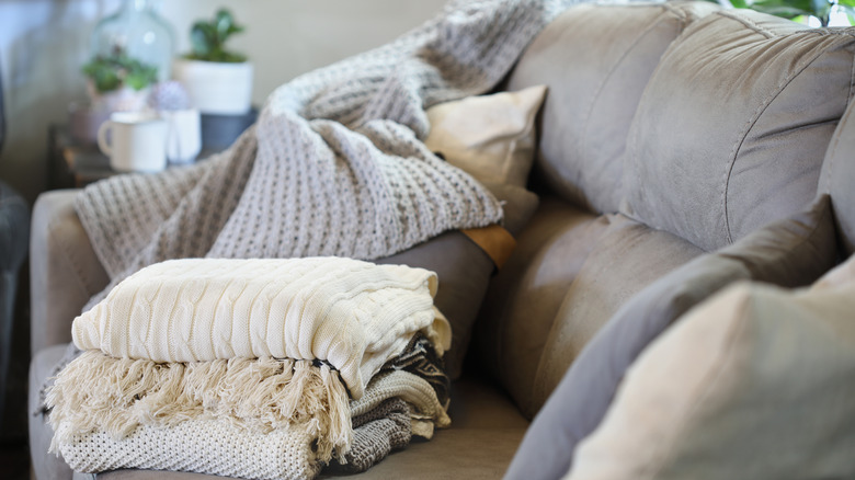 Throw blankets sitting in a pile on a couch in the living room.