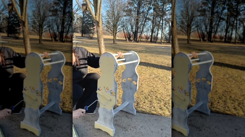 Person refinishing an old quilt rack outdoors