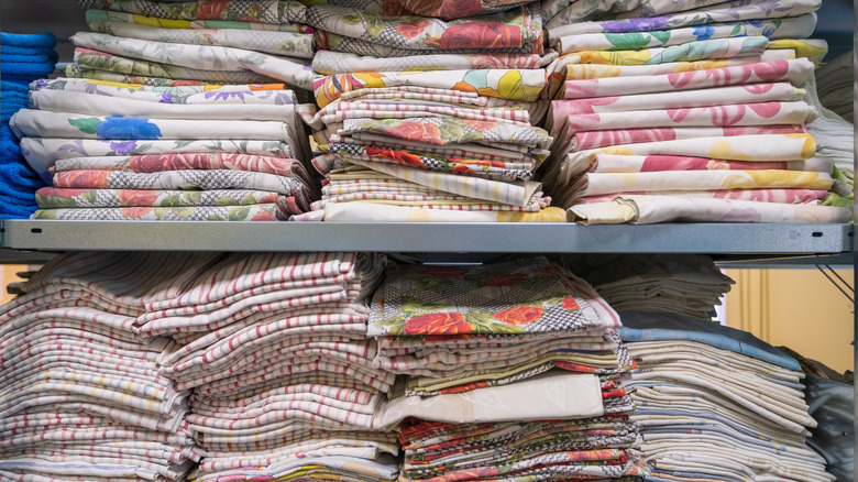 Stacks of different textiles ad fabrics on metal shelves, likely at a store