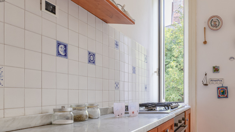 A white kitchen backsplash with blue accent tiles