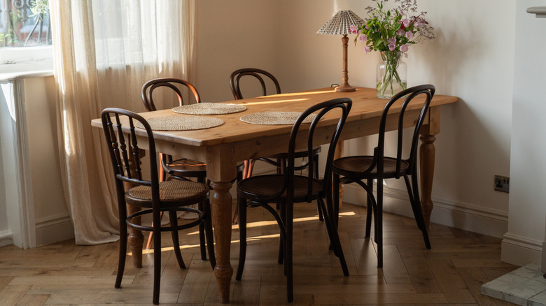 A dining room with a farmhouse-style table and refinished vintage chairs.