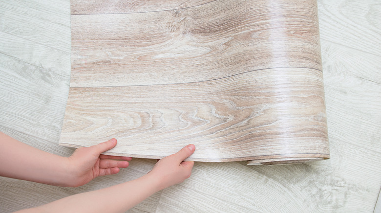 Hands holding rolled vinyl flooring