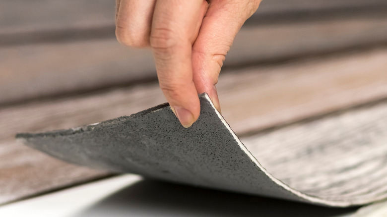 Hand peeling back potential vinyl floor options