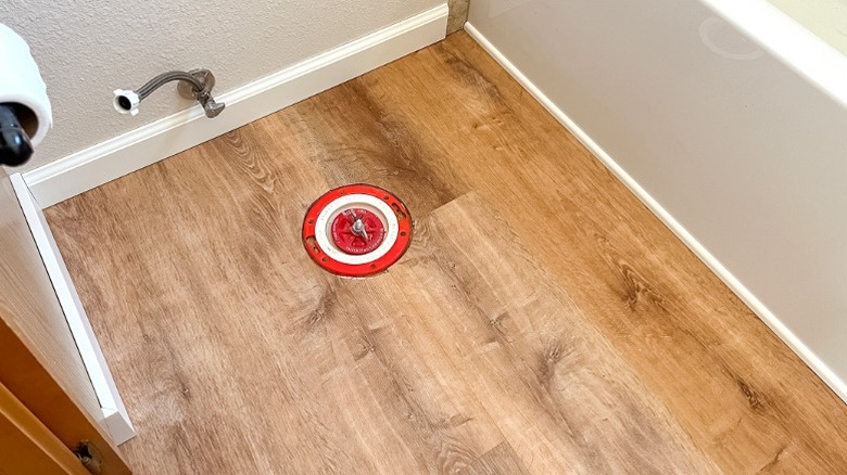 Wood-textured vinyl flooring in bathroom with removed toilet