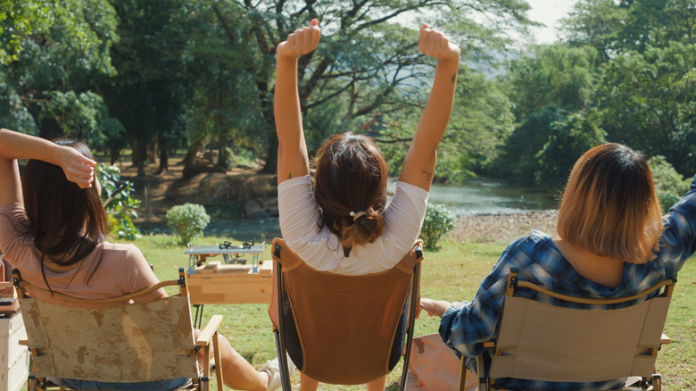 Three women sitting in hammock chairs outside