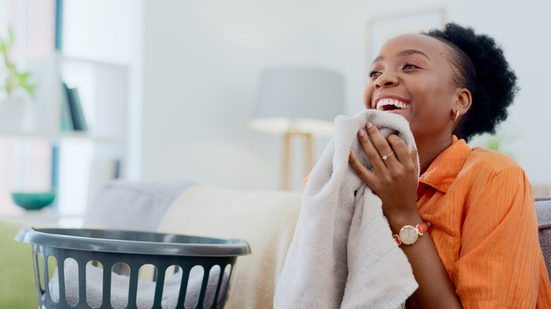 A woman smiles as she smells her clean clothes