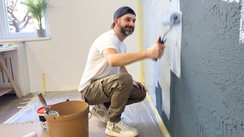 person painting with painter's tape on wall