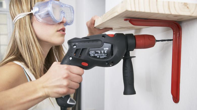 woman drilling red shelf bracket