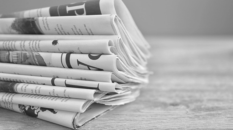 A stack of newspapers on a gray wooden surface