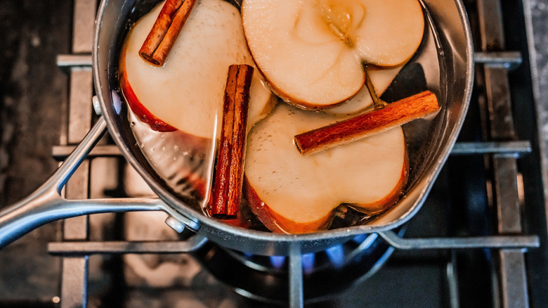 Pot simmering with apple slices and cinnamon sticks