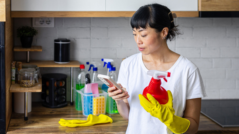woman checking phone and cleaner