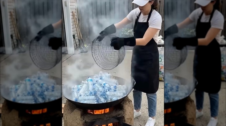 A fire pit filled with plastic water bottles and a woman standing next to it holding a wire basket.