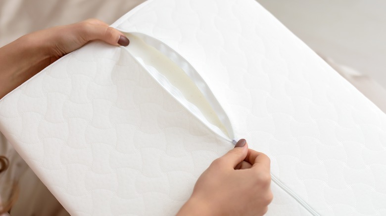 hands unzipping white cushion