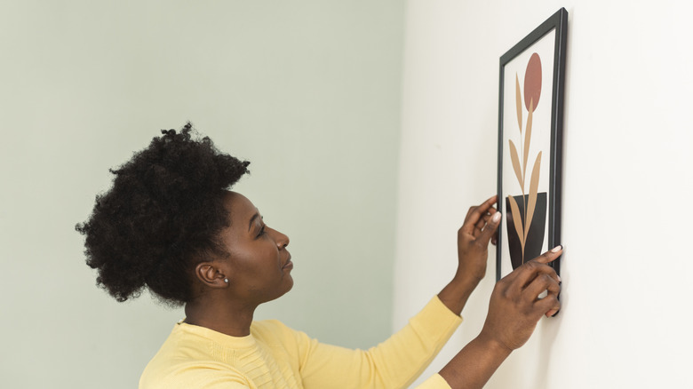 A person hanging art on the wall