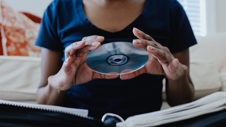Person holding CD above a storage binder