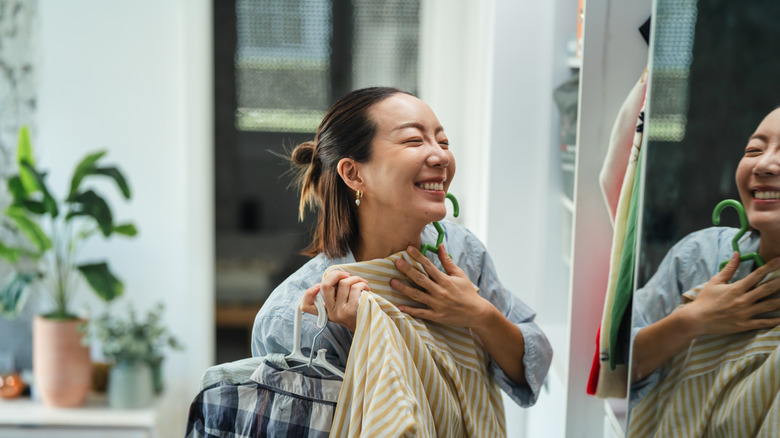 A woman smiles in front of a mirrored wardrobe.
