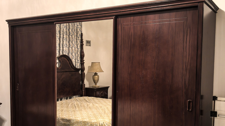 Mirrored wardrobes reflecting a bed.