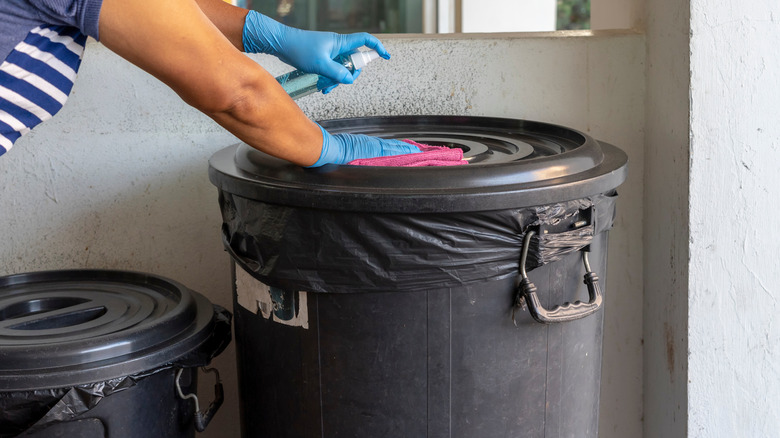 Person wiping trash can lid