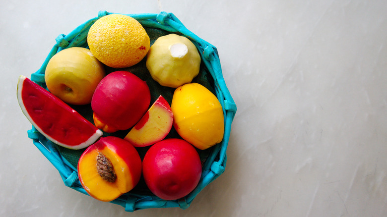 A blue bowl containing a variety of fruit-shaped soaps