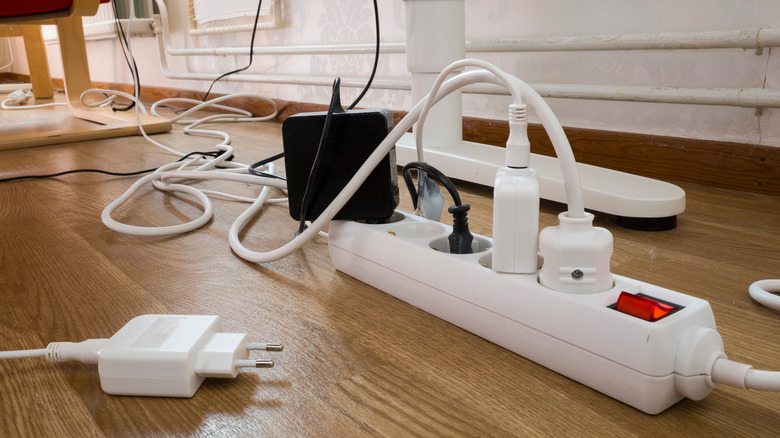 Ground level photo of various chargers and cords plugged into a power strip