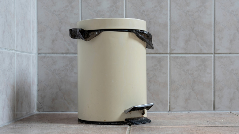 Close up of a bathroom trashcan with a lid and foot pedal