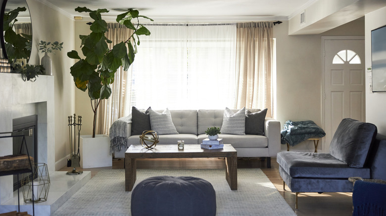 Neutral curtains cover a large window in a direct entry living room