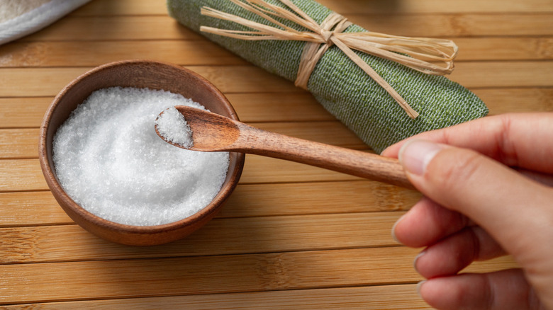Person scooping spoon of salt from bowl