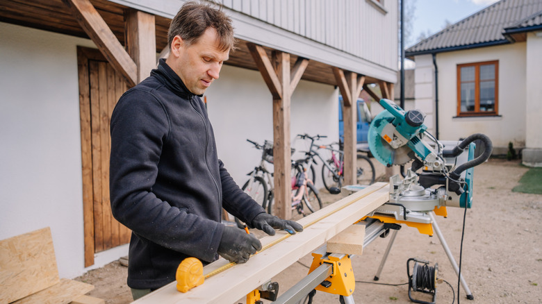 Man marking a board for cutting with a miter saw