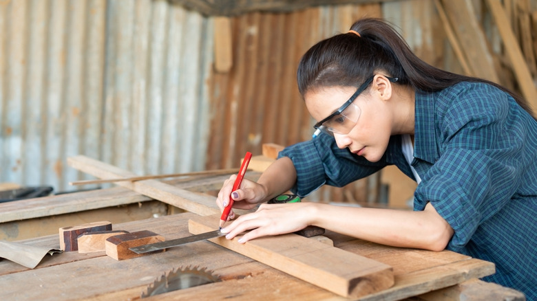 A person marking wood with a ruler