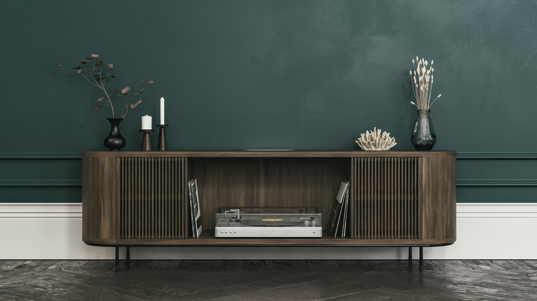Dark wood media cabinet against a green wall
